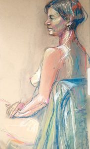 Back/side 3/4 view of female model with short bob and pearl earring. Model is leaning on green fabric draped over a chair back.